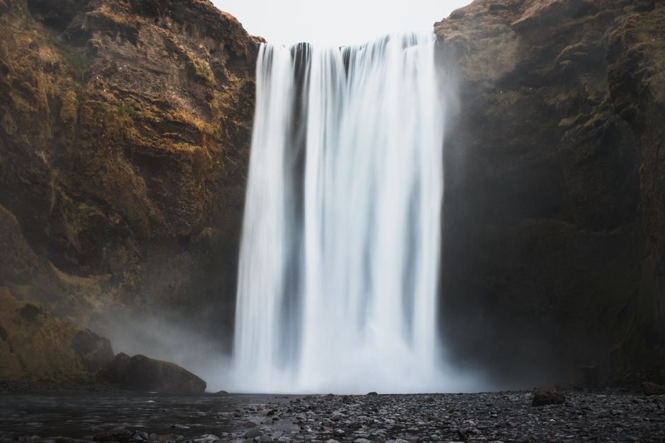 Breathtaking view of Skógafoss, a majestic waterfall in Iceland with mist and lush cliffs.